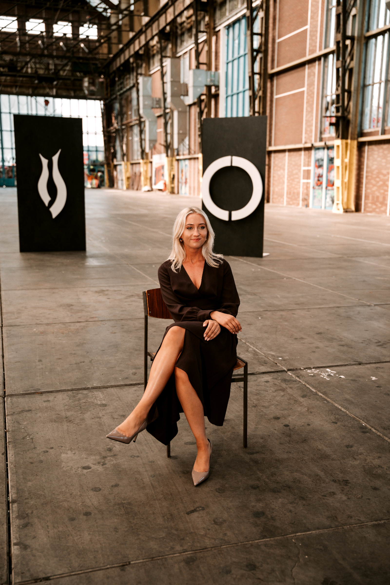 Kiki Brusché seated among sculptural works in an industrial hall